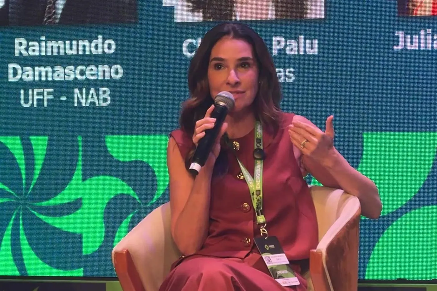Juliana Benício ao microfone durante painel em evento acadêmico na UFF