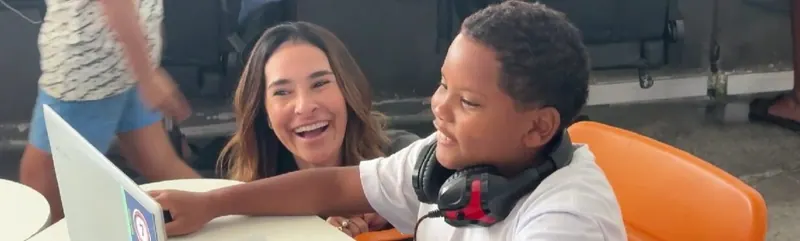 Juliana Benício com um aluno de fones em atividade na Plataforma Urbana Digital