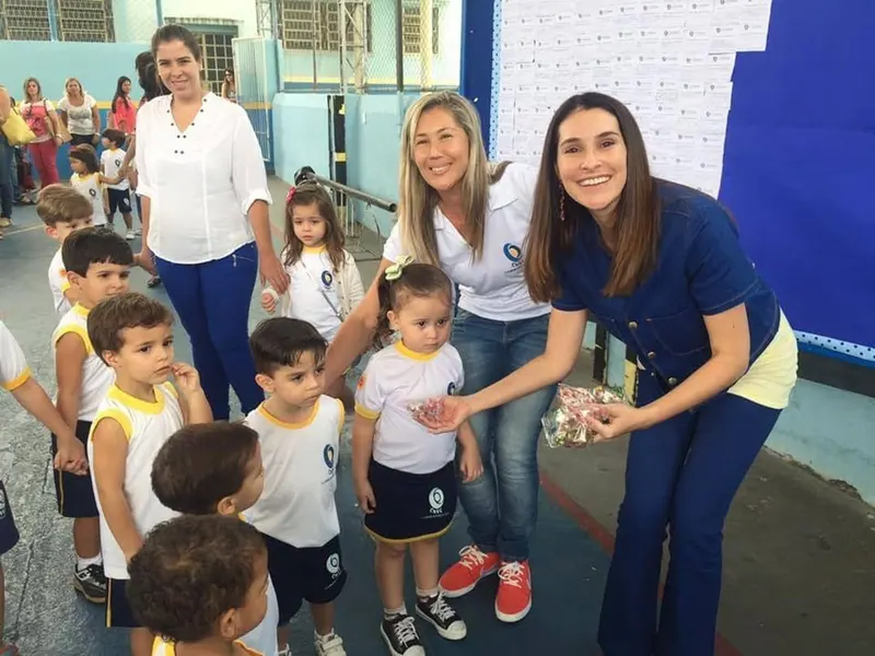 Juliana Benício com crianças e professora em uma escola